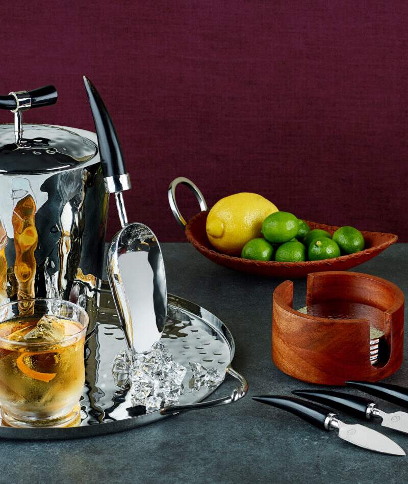 An ice bucket, ice scoop, and cocktail on a stainless steel serving tray