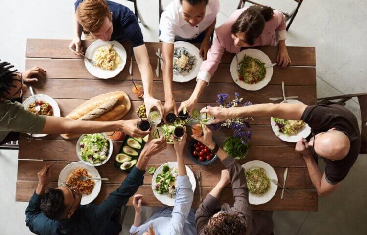 A group of friends sitting around a table toasting wine