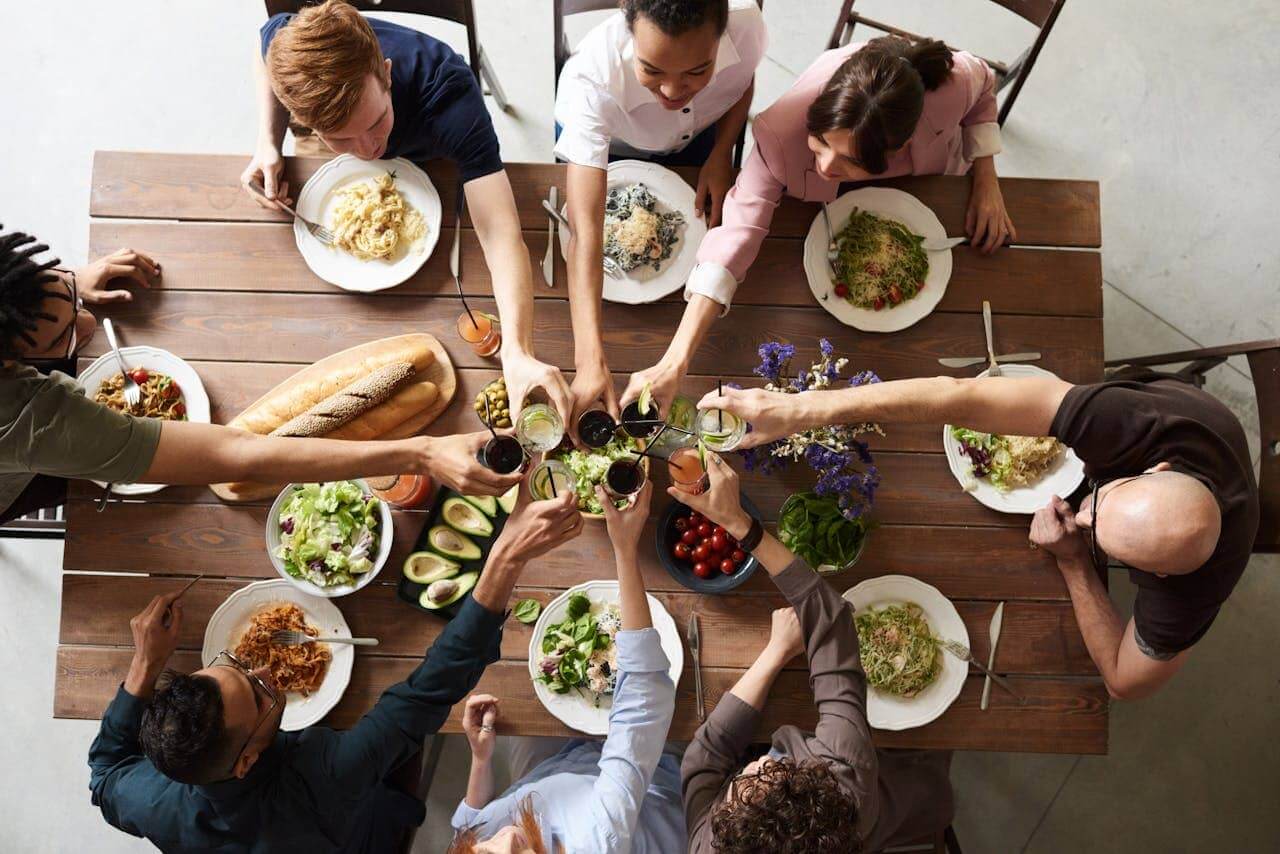 A group of friends sitting around a table toasting wine