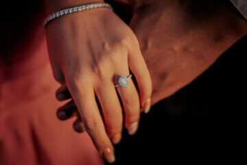 A couple holding hands wearing an engagement ring