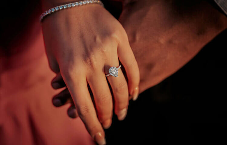 A couple holding hands wearing an engagement ring