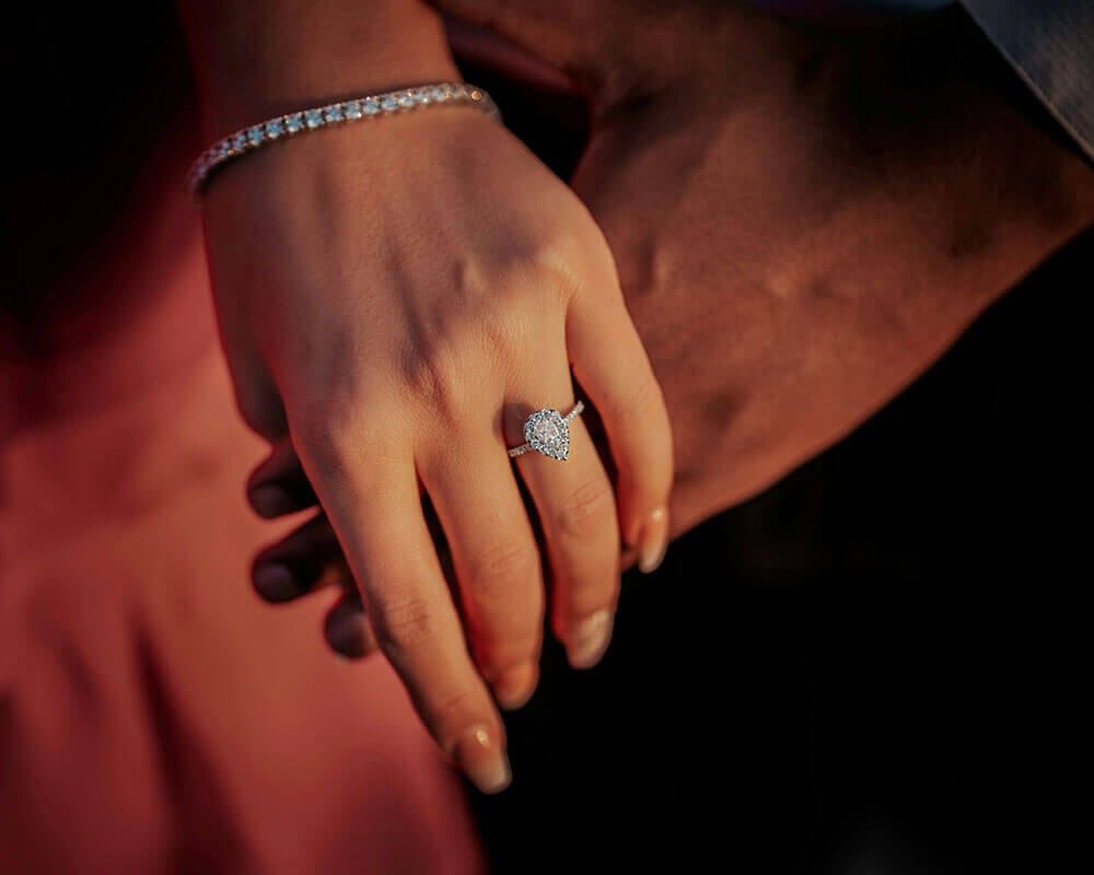 A couple holding hands wearing an engagement ring